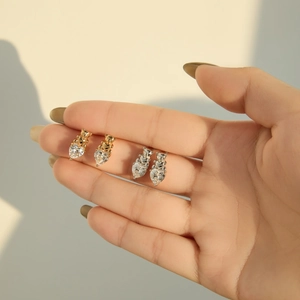 Détail de boucles d'oreilles ours avec cœur en zircon brillant, finitions or et argent