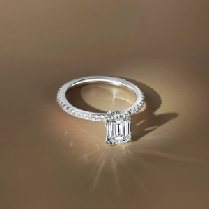 Detail of emerald cut gemstone ring with sparkling pavé setting and silver band