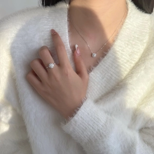 Gros plan sur l'ensemble collier et bague halo en argent sterling S925 sur pull blanc