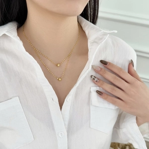 Double layered gold necklace with bead pendants worn on a stylish white shirt