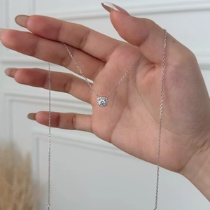 Gros plan d'un pendentif halo en moissanite 0,5 ct sur collier en argent S925 en main
