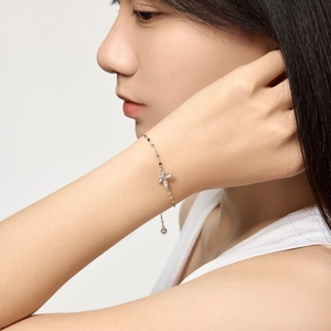 Macro detail of S925 silver bracelet with sparkling flower pendant on a female wrist