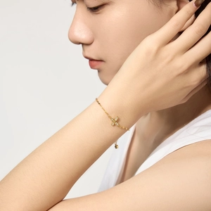 Macro shot of gold floral charm bracelet with zircon inlay on a model's wrist