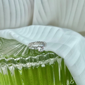 Macro shot of 2-carat sparkling round-cut silver ring on elegant green glass texture