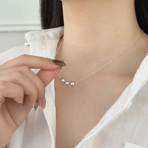Close-up of minimalist S925 sterling silver necklace featuring three polished round beads