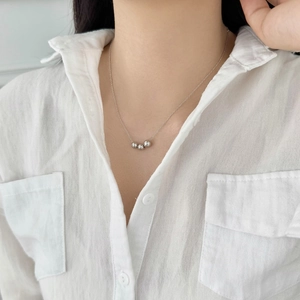 Close-up of minimalist S925 sterling silver necklace featuring three smooth round beads