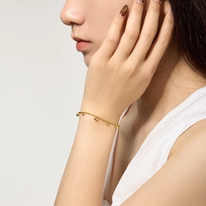 Gros plan d'un bracelet à double chaîne dorée et perles sur le poignet d'une femme
