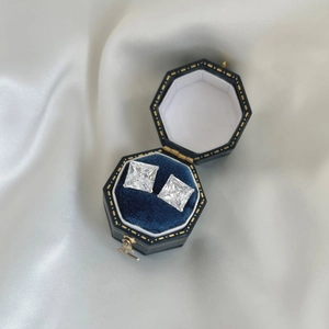 Detailed close-up of 3-carat square cut silver studs in a blue velvet jewelry box
