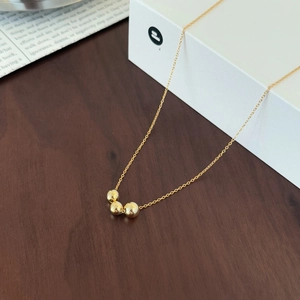 Detailed macro view of three polished gold beads on a minimalist S925 silver chain