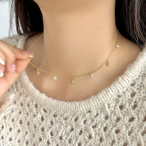 Detail of S925 sterling silver necklace with gold star charms and zircon pendants on a model