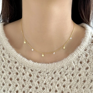 Detail of gold star pendant necklace with cubic zirconia on a knit sweater backdrop
