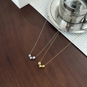 S925 sterling silver necklace featuring three smooth polished metal beads on dark wood background