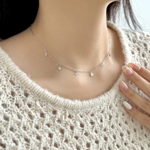 Close-up of S925 sterling silver star necklace with zircons on a white knit sweater
