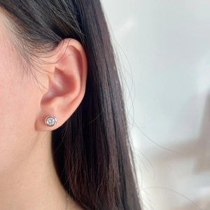 Close-up of minimalist S925 sterling silver solitaire stud earring worn on earlobe