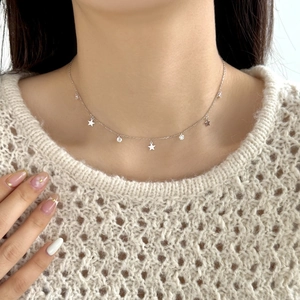 Detail of S925 silver necklace with sparkling star charms and zircons on female neck