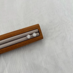 Close-up of minimalist S925 sterling silver stud earrings with bezel-set round moissanite stones