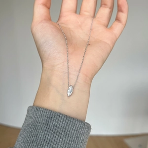 Gros plan détaillé du pendentif en moissanite taille marquise sur une chaîne en argent