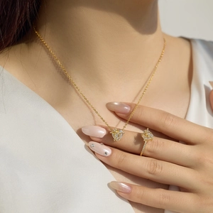Dettaglio di un elegante set di collana e anello a cuore in oro con zirconi su modella