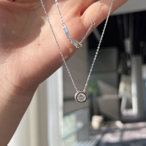 Macro detail of s925 sterling silver necklace featuring a round moissanite bezel pendant