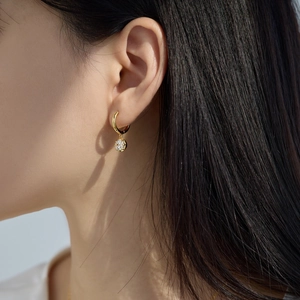 Close-up of a gold-plated hoop earring with a sparkling round zircon stone on model
