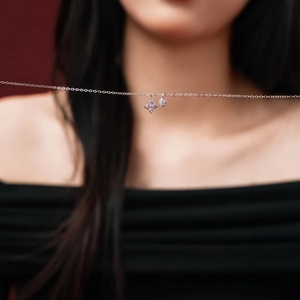Macro shot of silver clover necklace with purple stones and a clear zircon pendant