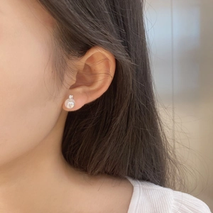 Close-up of minimalist S925 silver stud earring with white pearl and sparkling zircon