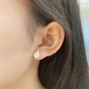 Close-up of minimalist S925 silver stud earring with white pearl and sparkling zircon