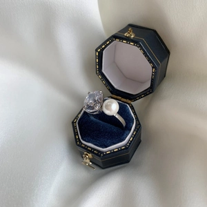 Détail d'une bague en argent avec zircon ovale et perle blanche dans son écrin bleu