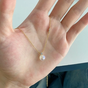 Détail macro du collier en argent S925 doré avec pendentif rond en pierre de lune irisée