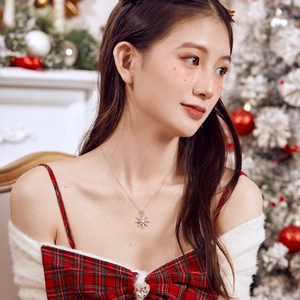 Close-up of snowflake pendant necklace with pearl on woman in Christmas setting