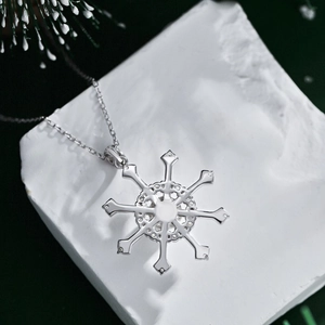 Macro shot of silver snowflake pendant on a fine cross chain against a marble block