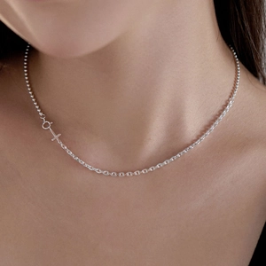 Detail of 925 sterling silver layered necklace with cross pendant on model neck
