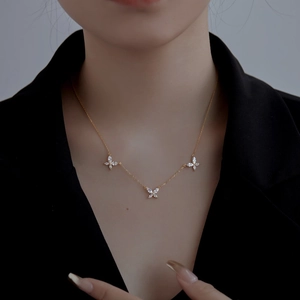 Gros plan d'un collier papillon en or avec zircons porté par un mannequin en noir