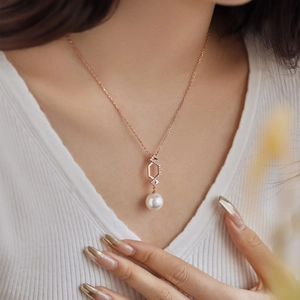Detail of rose gold hexagon pendant with zircon accents and a round freshwater pearl