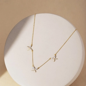 Détail du collier papillon doré orné de zircons marquise sur un présentoir en pierre