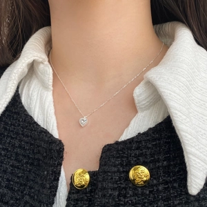 Close-up of heart-shaped zircon necklace on model wearing a chic tweed jacket