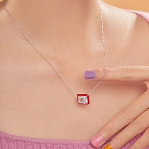 Close-up of a square zircon pendant necklace with a red enamel border on a model