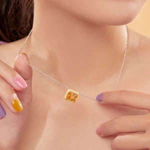Macro detail of square orange zircon pendant with gold-plated trim on S925 silver chain