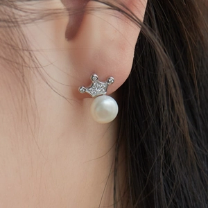 Macro detail of S925 silver crown earrings with freshwater pearl on a model's ear