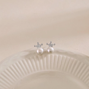 Close-up of S925 silver crown earrings with freshwater pearls on a ceramic dish