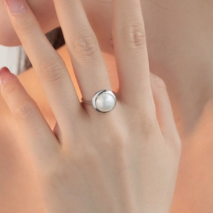Close-up of elegant S925 silver ring featuring a round white freshwater pearl on finger