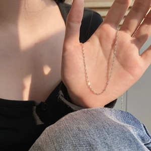Close-up of slender S925 sterling silver water wave chain necklace held by model