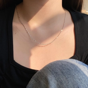 Detail of delicate S925 sterling silver chain necklace worn on a square neck top