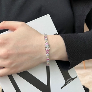 Detail of colorful V-shape zircon tennis bracelet on wrist with a minimalist background