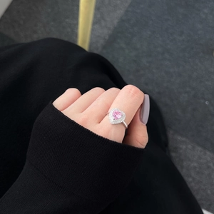Gros plan d'une bague en argent S925 avec un zircon rose en forme de cœur au doigt