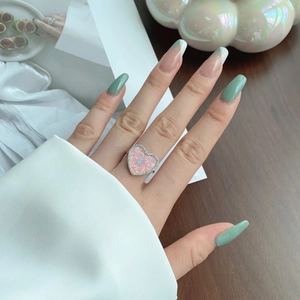 Close-up of heart-shaped pink opal ring with diamond halo on model's hand