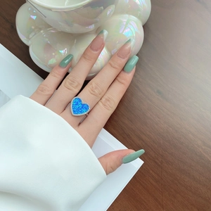 Close-up of heart-shaped silver ring featuring a blue opal stone and zircon pavé