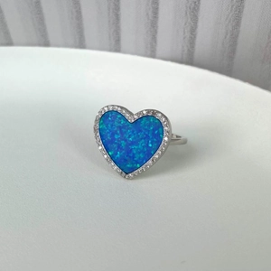 Macro shot of silver heart ring with sparkling blue opal center and halo zircon setting