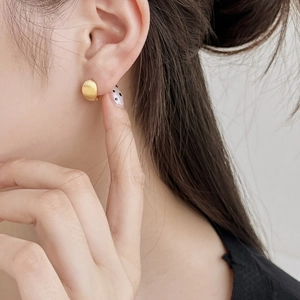 Elegant round brushed gold stud earrings in S925 sterling silver worn by a model