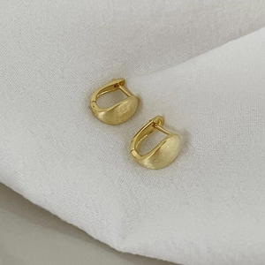Macro shot of minimalist gold brushed S925 sterling silver earrings with textured finish